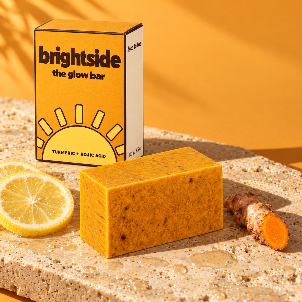 The Glow Bar and its brightside box on wet stone with lemon and fresh turmeric